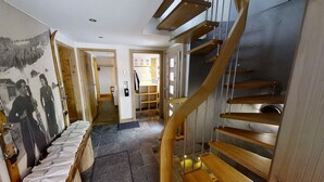A spiral staircase with wooden steps and metal railings, leading to a landing with a door and a bulletin board. - GUEST CHALET WHITE FANG / CROC BLANC CHALET RELAXING 4 SAISONS (Morzine)
