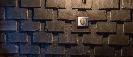 Un salon moderne avec un mur en pierre et un luminaire noir fixé au mur.