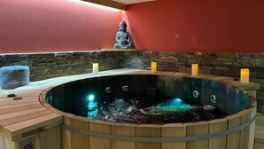 A hot tub with a Buddha statue, stone wall, and candles. - GUEST CHALET WHITE FANG / CROC BLANC CHALET RELAXING 4 SAISONS (Morzine)