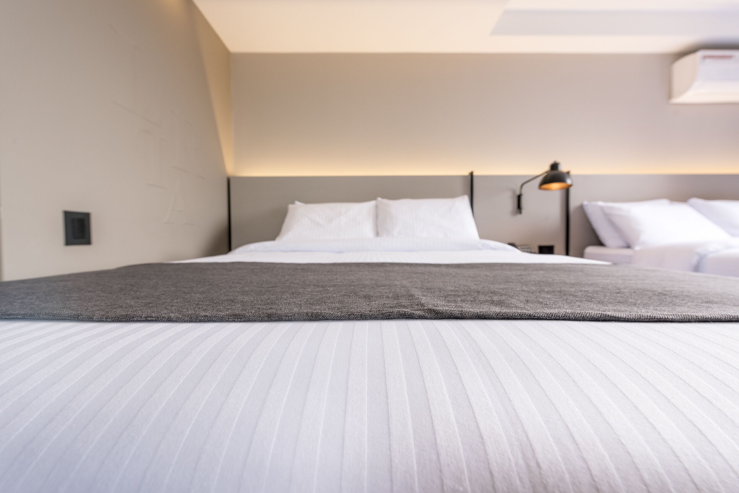 Une chambre d’hôtel moderne avec un grand lit, une table de chevet et une lampe.
