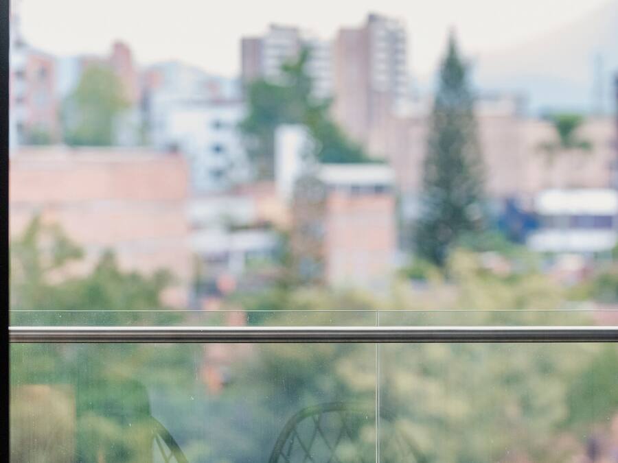 Dos sillas de alambre negro frente a una ventana con vista a la ciudad.