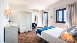 Une chambre à coucher avec un lit, une commode, une chaise et une fenêtre avec des rideaux.