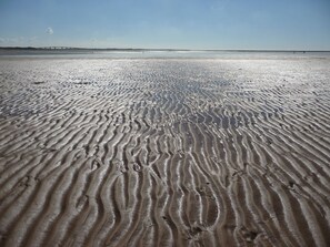 A sandy beach with rippled patterns, a clear sky, and a distant bridge. - House in Barbâtre on the Île de Noirmoutier. Wi-Fi La Cheminée 56 m² -------- (Barbâtre)