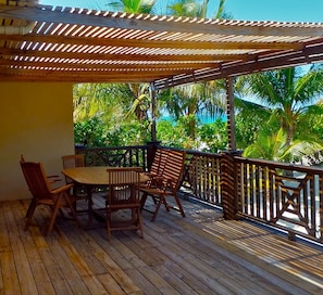 Enjoy a tranquil atmosphere on the deck with a table and chairs, surrounded by lush tropical vegetation and palm trees.
