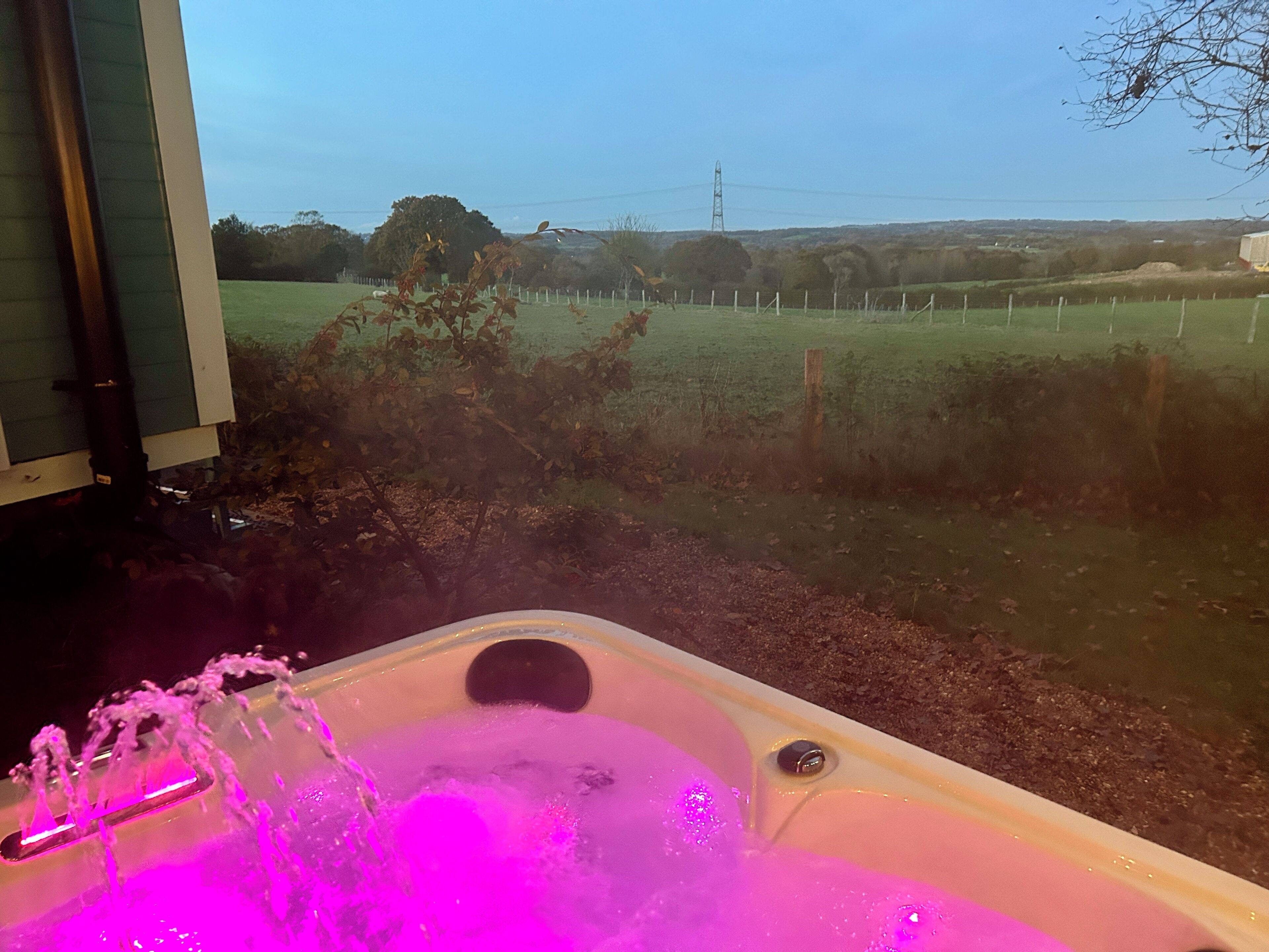A hot tub with water jets and a view of a grassy field and a building in the background.
