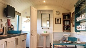 Una cocina compacta con lavamanos, un televisor y un comedor con mesa y sillas.