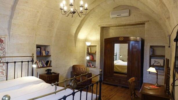 A bedroom with a bed, a chair, a desk, a bookshelf, a mirror, and a chandelier. - 3-Bedroom Stone House with a View (Nevşehir)