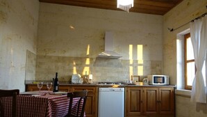 A kitchen with a wooden table set for dining, a microwave, and a dishwasher. - 3-Bedroom Stone House with a View (Nevşehir)