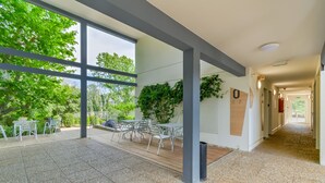 A spacious indoor area with large windows, a wooden deck, and a seating area with tables and chairs. - B&B HOTEL Marseille La Valentine (Marseille)