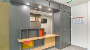 A reception area with a counter, a door, and a wall-mounted plan intervention poster. - B&B HOTEL Marseille La Valentine (Marseille)