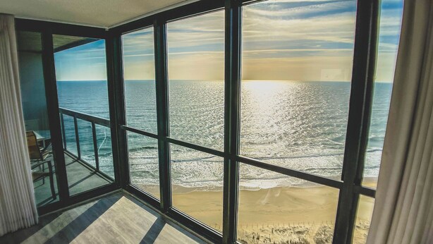 Ein Zimmer mit großen Fenstern und Meerblick auf den Strand.