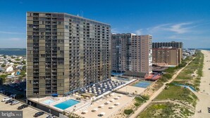 Ein Hochhotel mit mehreren Etagen, einem Poolbereich und Blick auf den Strand.