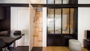 Une pièce moderne et compacte comprenant un coin repas, un escalier menant à une chambre en mezzanine et une salle de bain visible.