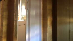 Un couloir étroit aux murs en bois, avec une porte donnant sur une pièce dotée d’une fenêtre.