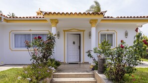 Una casa con techo de tejas, una puerta blanca y un conjunto de escalones de hormigón que conducen a la entrada.