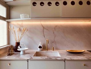 Una cucina moderna con un piano di lavoro in marmo, un rubinetto dorato e un design minimalista.