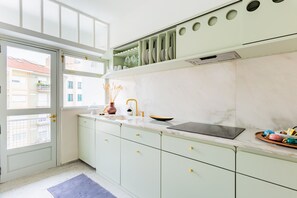 A modern kitchen with a marble countertop, a built-in oven, and a window overlooking a cityscape.
