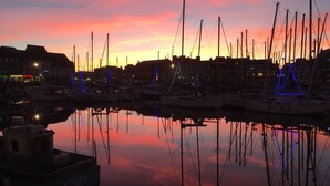 En småbåtshamn vid solnedgången, med båtar förtöjda och upplysta av blått ljus.