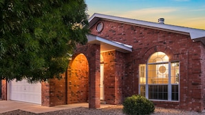 A brick house with a garage, two arched entryways, and a large window with a decorative glass design. - Hot tub with city views 
     -NO PARTIES ALLOWED- (Albuquerque)