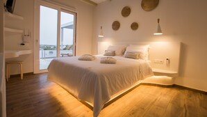 Un dormitorio con una cama grande, suelo de madera, un escritorio y vistas a través de un ventanal.
