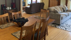 A dining area with a wooden table and chairs, a sofa, and a chandelier. - Centrally located for all your activities! (Colville)