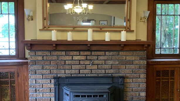 A fireplace with a brick surround, a wooden mantel, and a mirrored section above. - Centrally located for all your activities! (Colville)