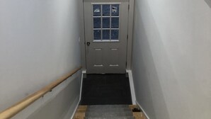 A narrow hallway with a wooden handrail, a white door with a window, and a wall-mounted compass decoration. - Wonderful Mid Island Gem (Nantucket)