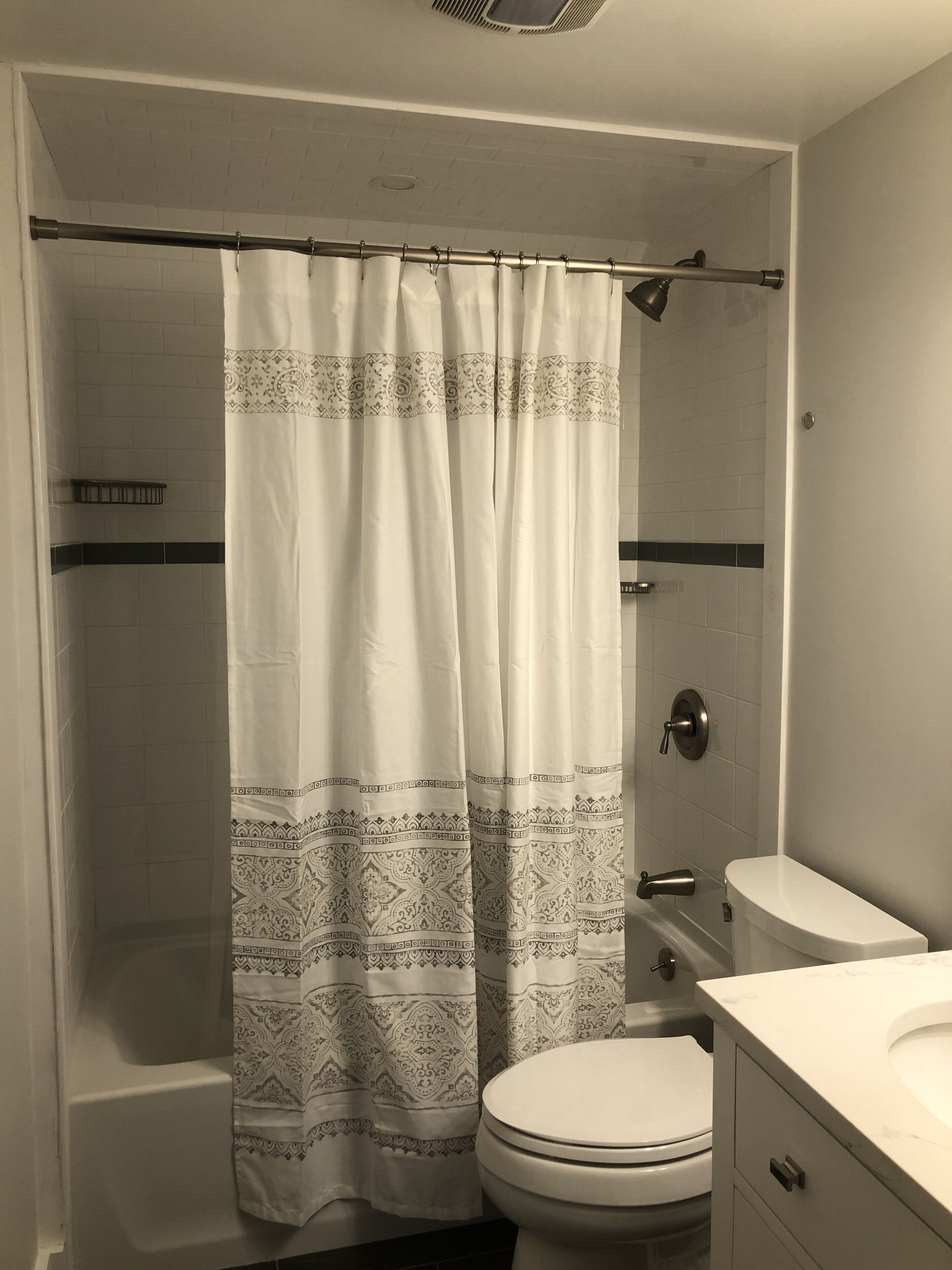 A bathroom with a shower curtain, toilet, and sink.