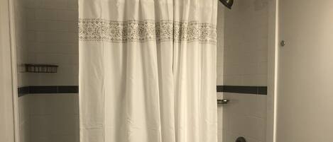 A bathroom with a shower curtain, toilet, and sink.