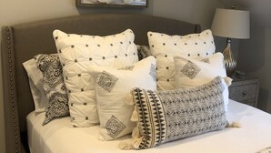 A neatly made bed with patterned bedding, a decorative wall piece above it, and a bedside lamp. - Wonderful Mid Island Gem (Nantucket)