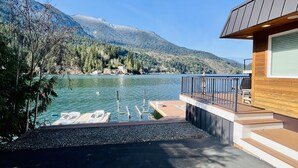 A lakeside property with a wooden deck, lounge chairs, and a view of the lake and mountains. - Dreamlike Lakefront Cabin on Lake Sutherland (Port Angeles)