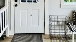 A white door with a window, a black metal dog gate, a framed deer head, and a sign on the wall. - Dreamlike Lakefront Cabin on Lake Sutherland (Port Angeles)