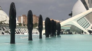 Il s’agit d’une structure architecturale moderne au design unique, caractérisée par un grand bâtiment blanc aux lignes courbes et une série de sculptures cylindriques sombres disposées au premier plan.