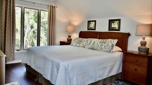 A neatly made bed with a patterned pillow, two bedside lamps, and a window with curtains. - Short, pleasant walk to the beach! Two bedrooms, two baths. Dogs OK. (Kiawah Island)