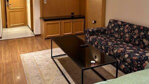 Un espacio habitable compacto con sofá, una mesita de centro, kitchenette y ventilador de techo.