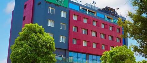 A multi-story hotel with a colorful facade, featuring a prominent Comfort logo and a Purple Basil sign.