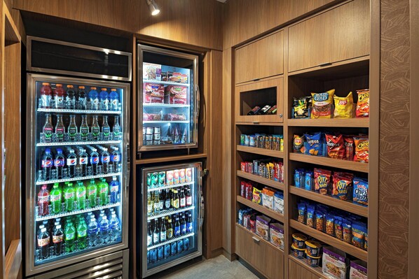 Una zona de máquinas expendedoras con varios dispensadores de bebidas y estantes con aperitivos.