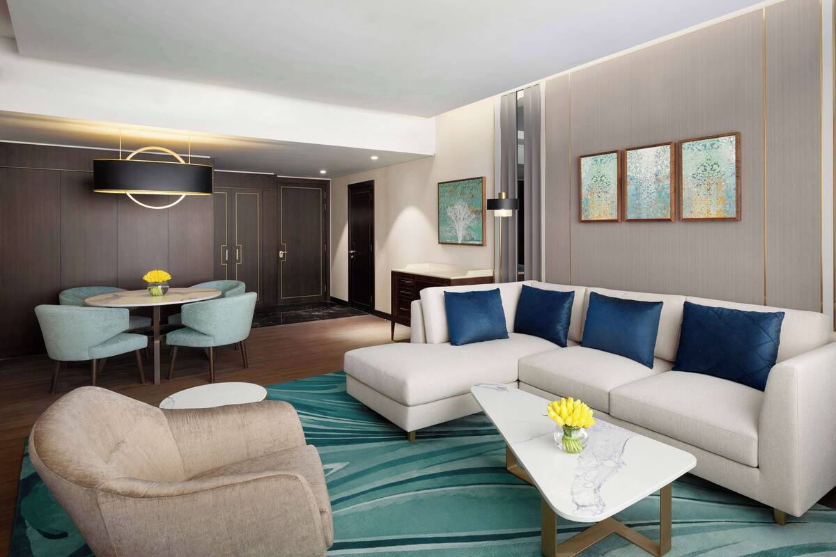 A modern living room with a sectional sofa, a round dining table, and a coffee table.