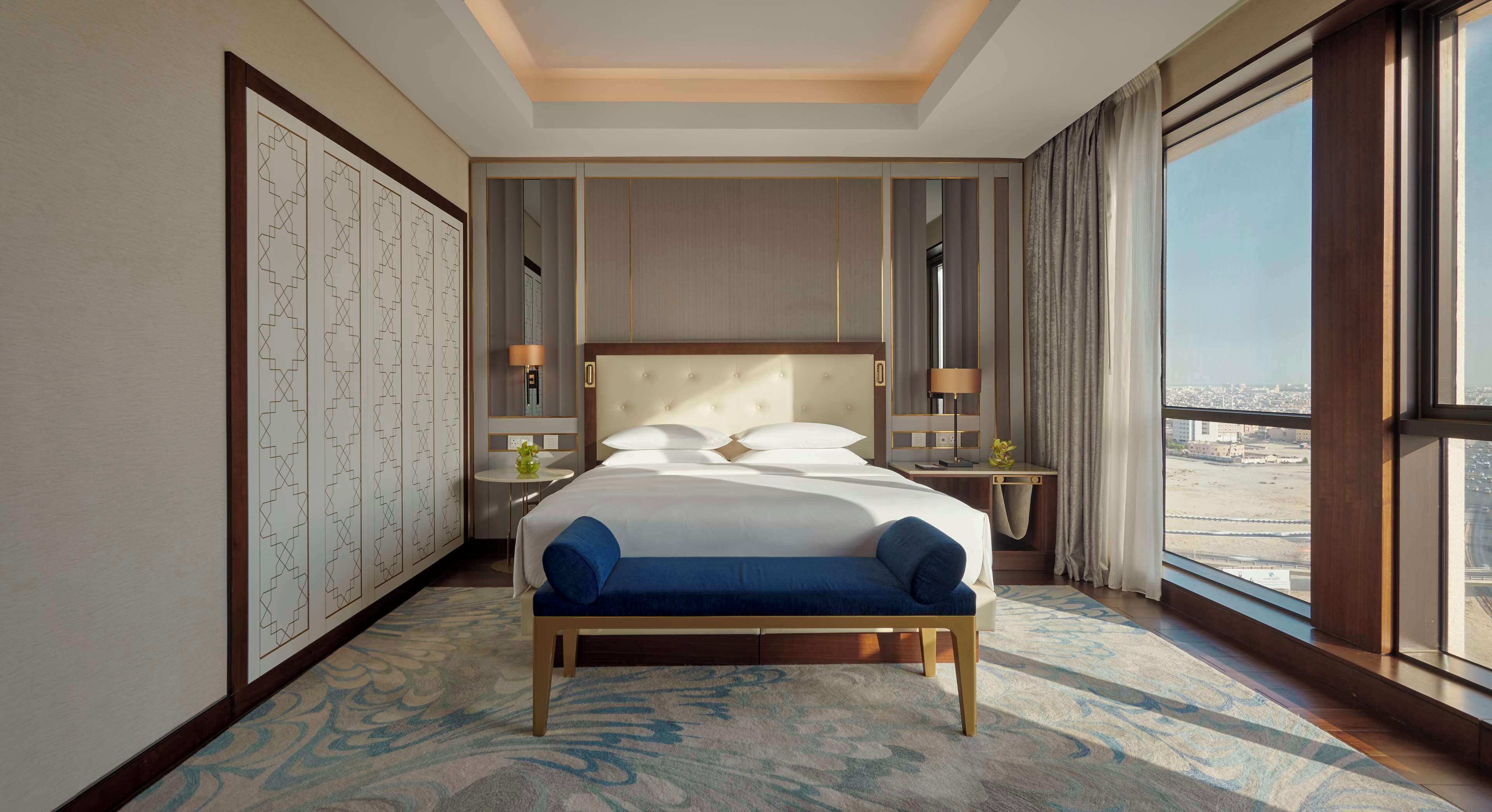 Una habitación de hotel con una cama grande, vistas a la ciudad y un panel decorativo en la pared.