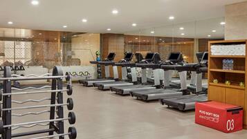 Un gimnasio moderno con cintas de correr, máquinas de pesas y mancuernas.