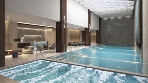 A modern indoor pool area with a clear pool, lounge chairs, and a bar area. - Grand Hyatt Alkhobar Hotel and Residences (Al Khobar)