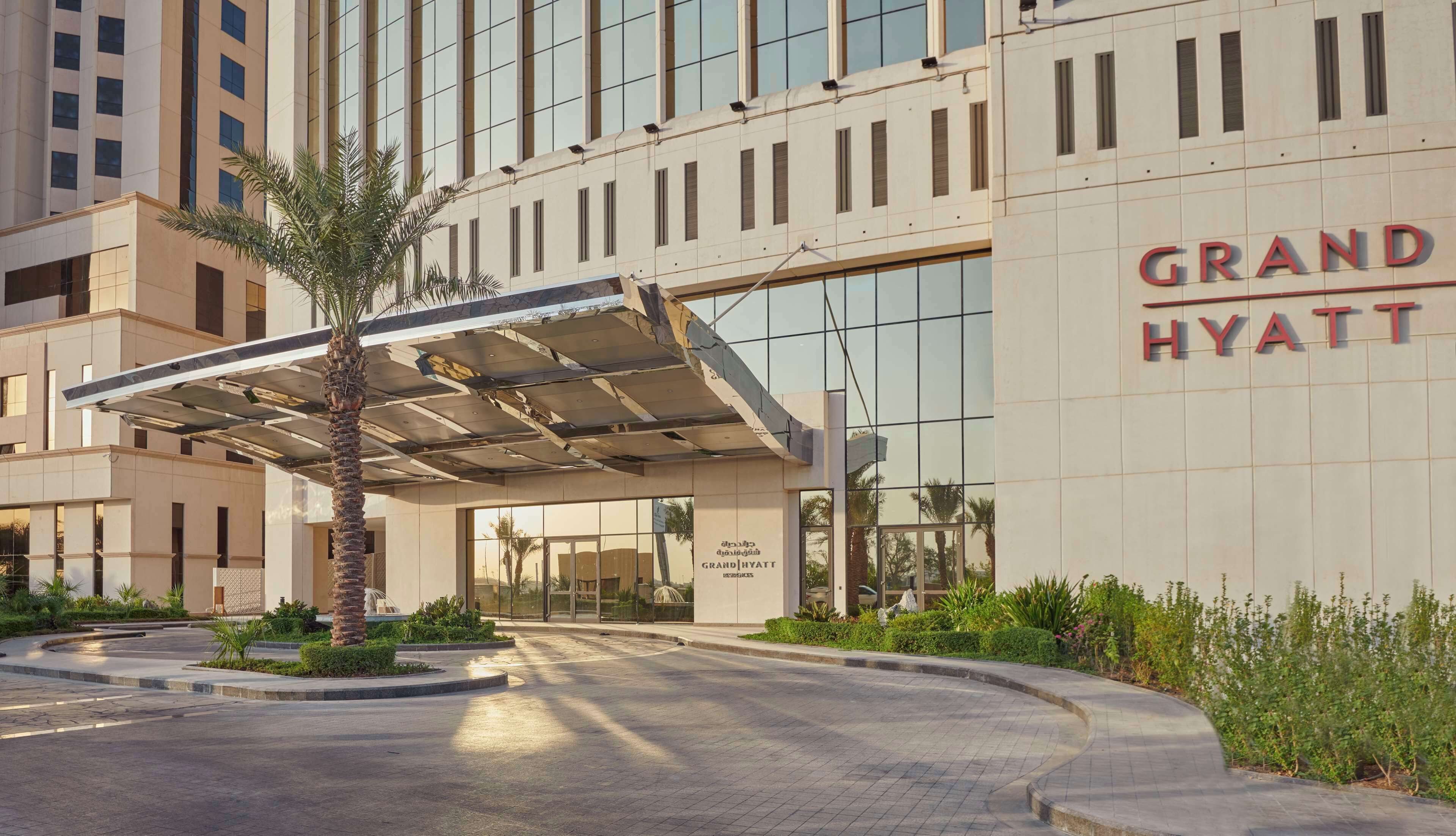 A Grand Hyatt hotel entrance with a covered walkway, palm trees, and a well-maintained garden.