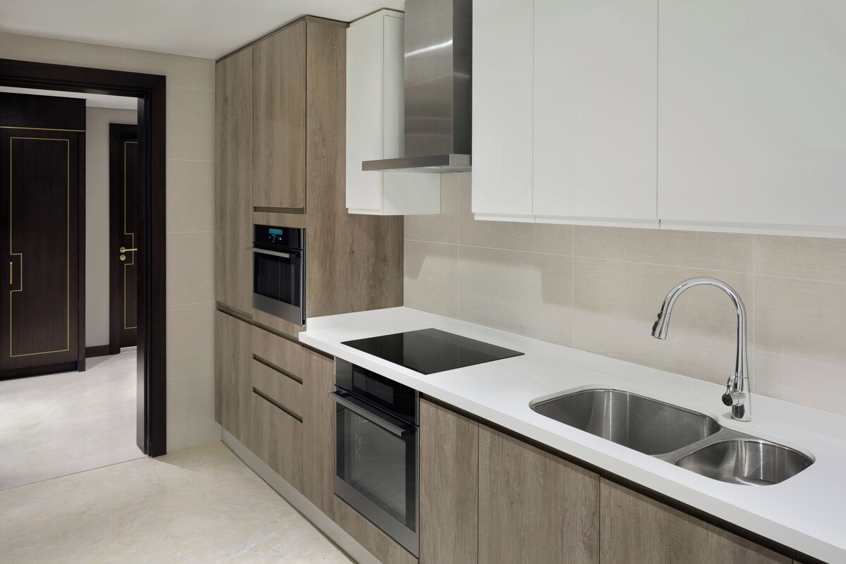A modern kitchen with a double sink, built-in oven, and wooden cabinetry.