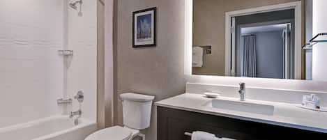 A modern bathroom with a bathtub, toilet, sink, and a large mirror.