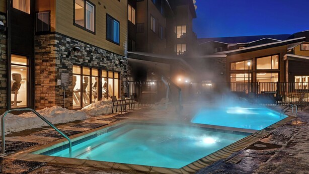 A heated outdoor pool area with a stone facade building, a covered seating area, and a clear night sky. - Residence Inn by Marriott Steamboat Springs (Steamboat Springs)