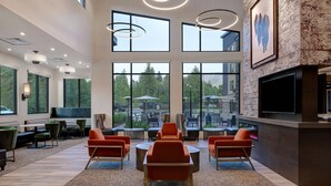 A spacious indoor area with multiple seating options, large windows, and a flat-screen TV mounted on the wall. - Residence Inn by Marriott Steamboat Springs (Steamboat Springs)