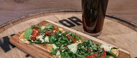 Dos pizzas sobre una tabla de madera con un vaso de cerveza al lado.