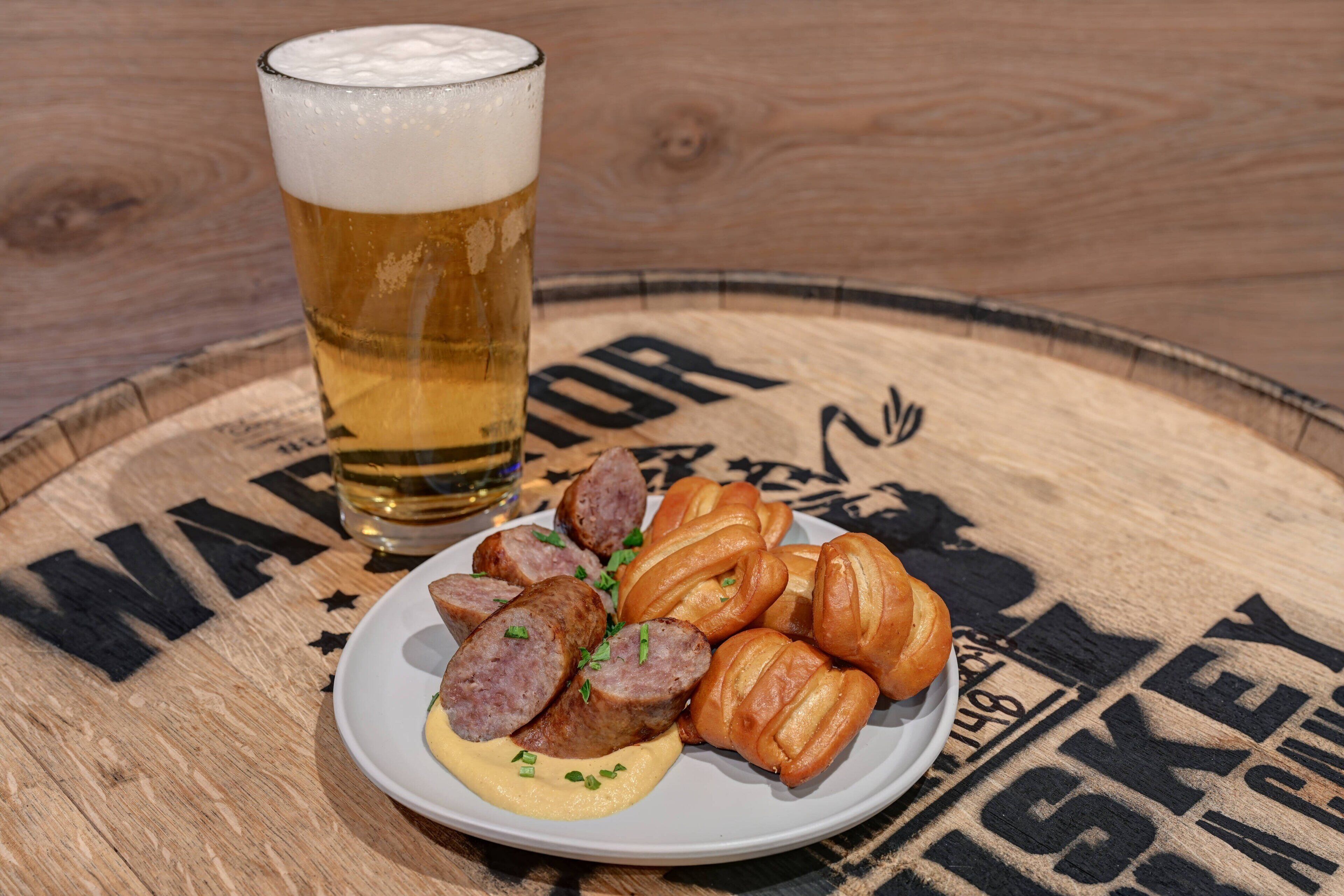 Une assiette de tranches de saucisson et de croissants sur une table en bois, avec un verre de bière.