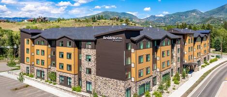 A multi-story hotel with a stone facade, multiple balconies, and a parking lot.
