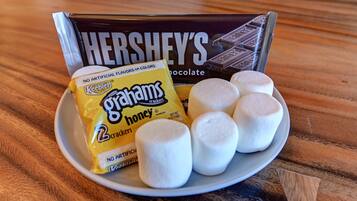 A plate with marshmallows, a pack of Ghirayams crackers, and a Hershey's chocolate bar.